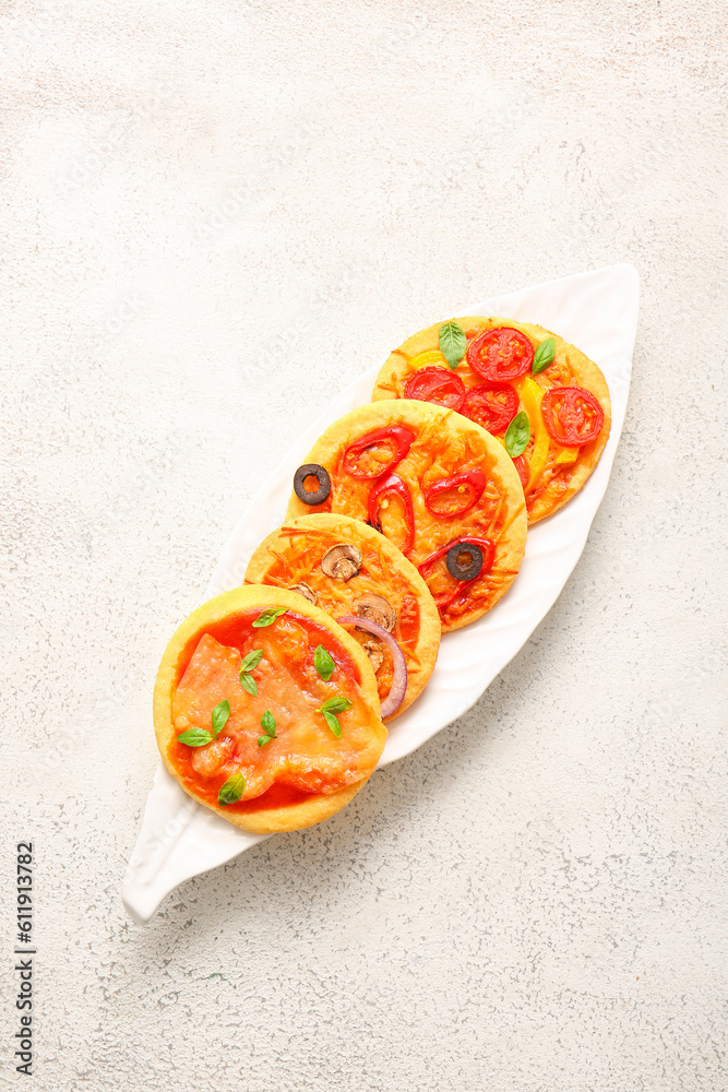 Plate with different tasty mini pizzas on white background