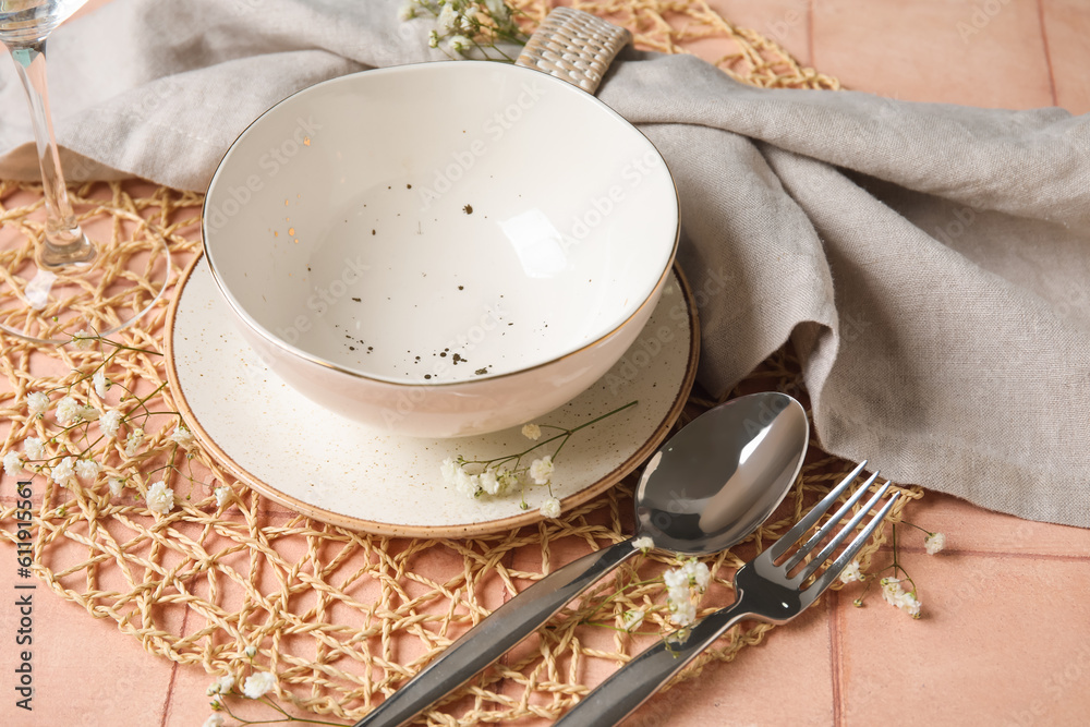 Wicker mat with stylish table setting on pink tile background