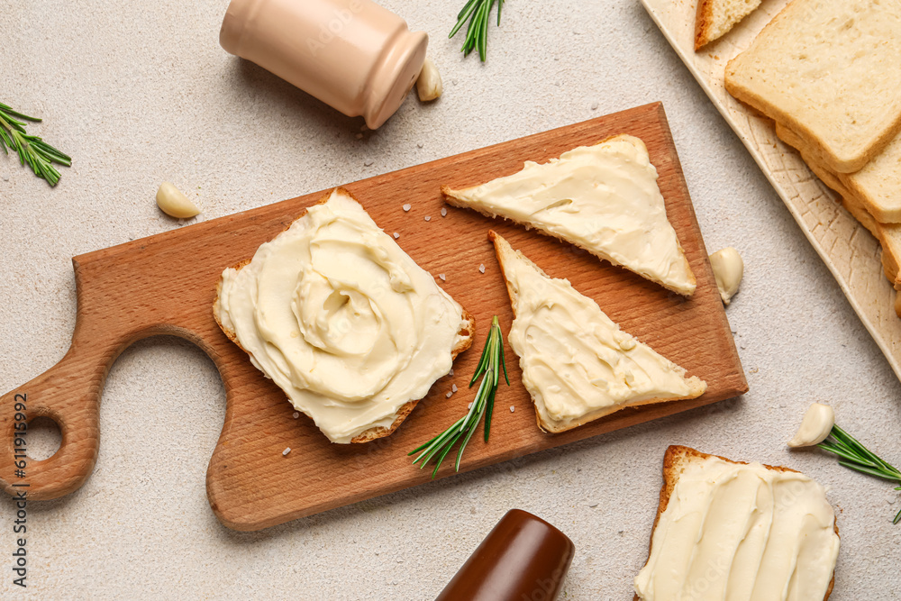 Wooden board of tasty toasts with cream cheese on light background