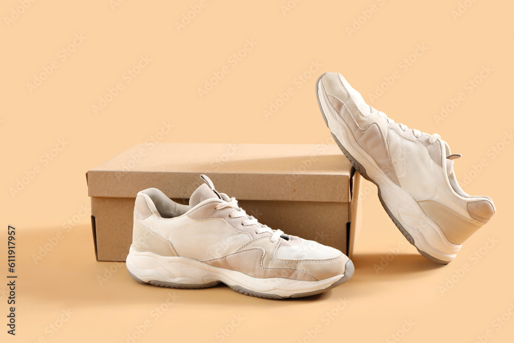 Cardboard box with stylish sneakers on beige background