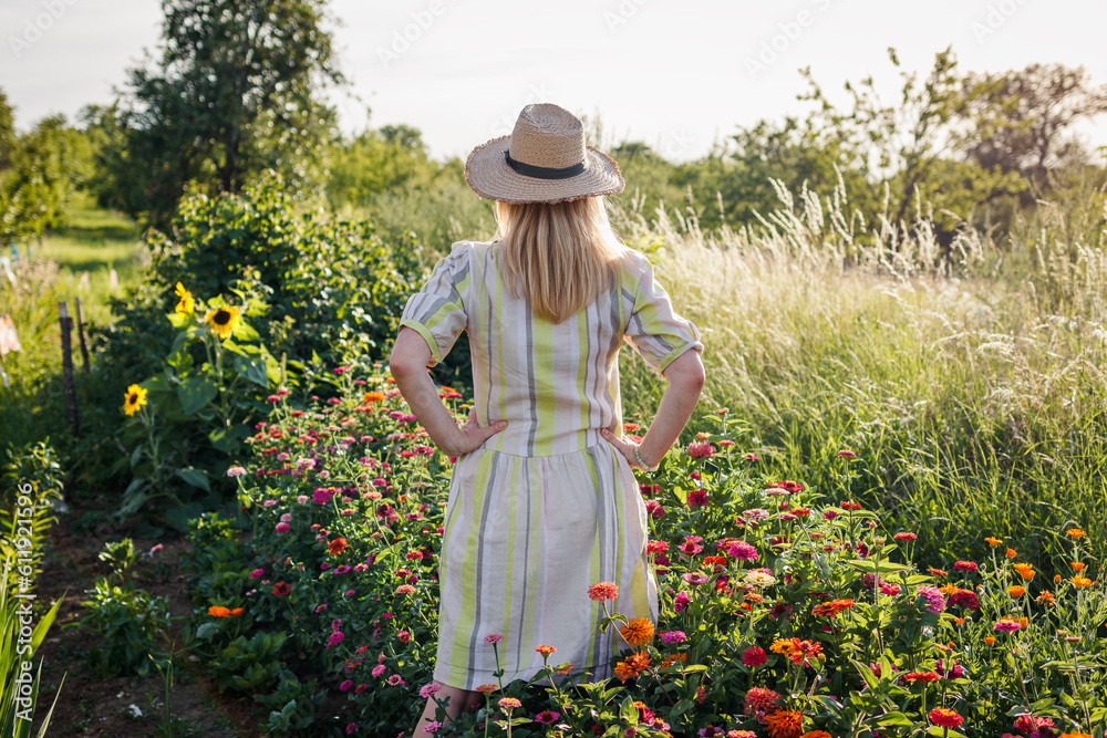 Woman standing in flower garden. Female florist relaxing and enjoying view at blooming floral farm i