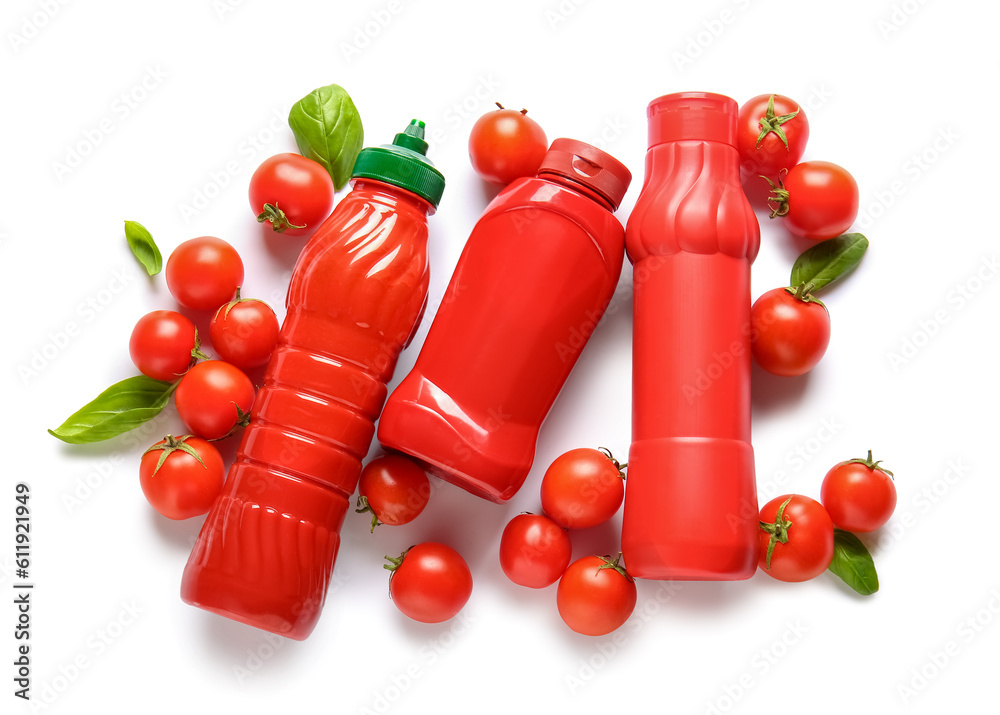 Bottles of ketchup and tomatoes on white background