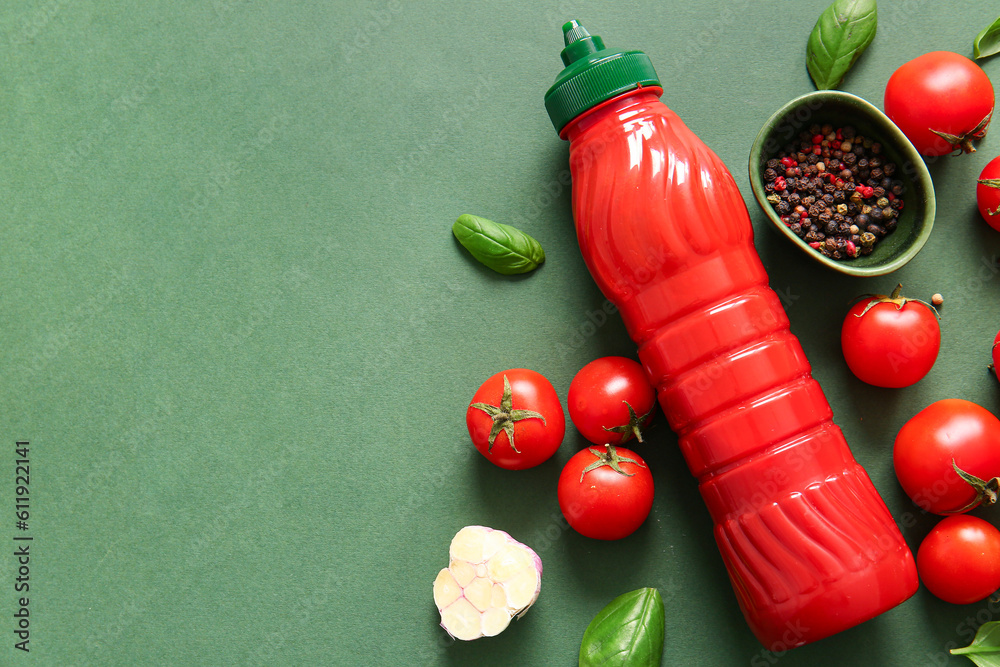 Bottle of ketchup and tomatoes with peppercorn on green background