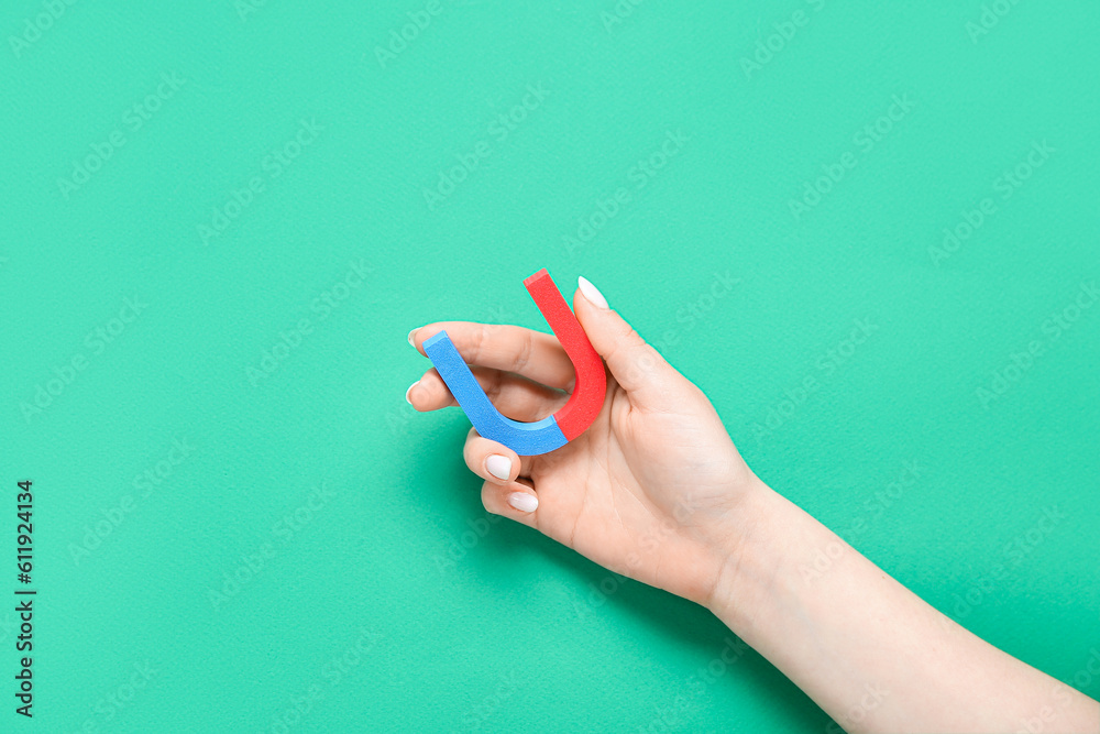 Female hand with mini magnet on green background