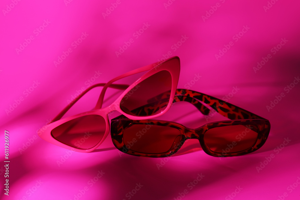 Different stylish sunglasses on pink background