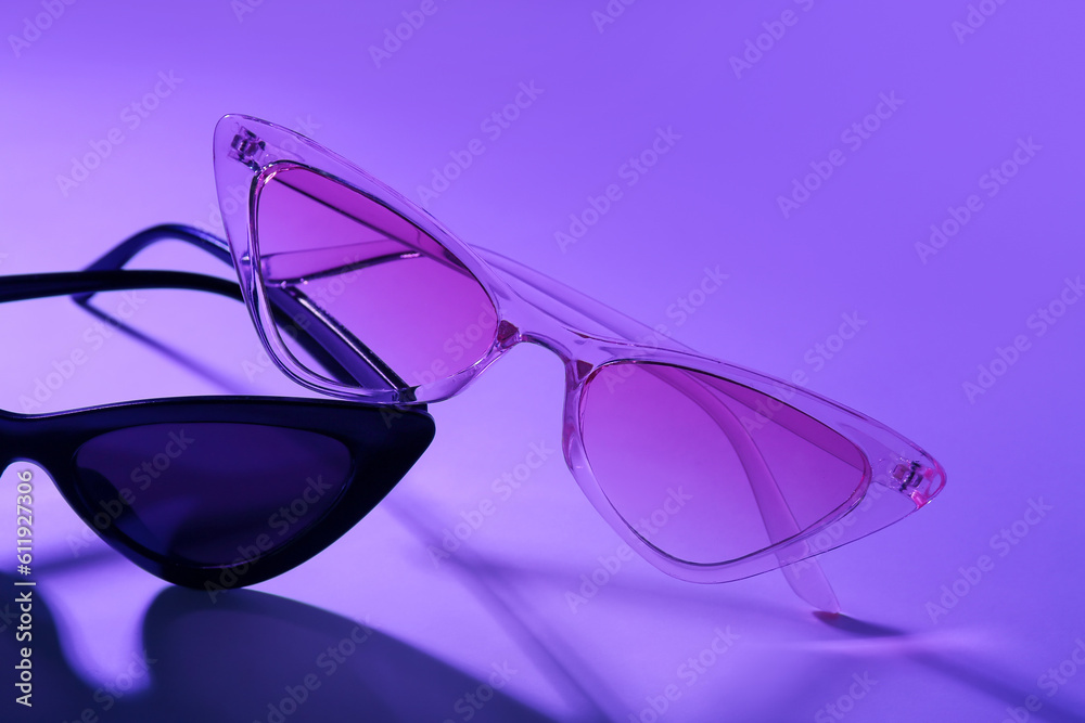 Stylish different sunglasses on purple background