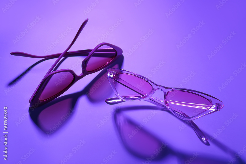 Stylish different sunglasses on purple background