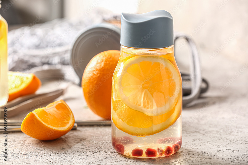 Sports bottle of infused water with orange slices on grey table