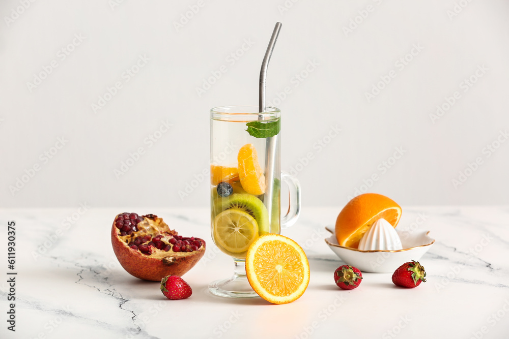 Glass of infused water with different sliced fruits on white table