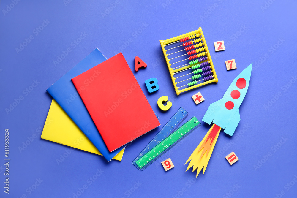 Paper rocket with abacus, wooden letters and different stationery on dark blue background