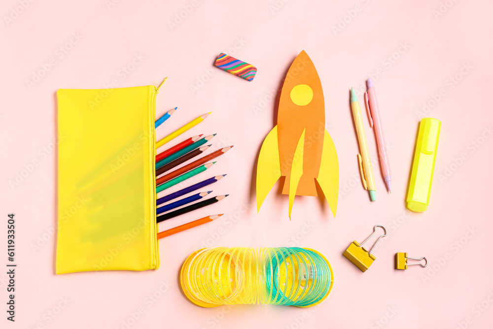 Paper rocket with pencil case and different stationery on pink background