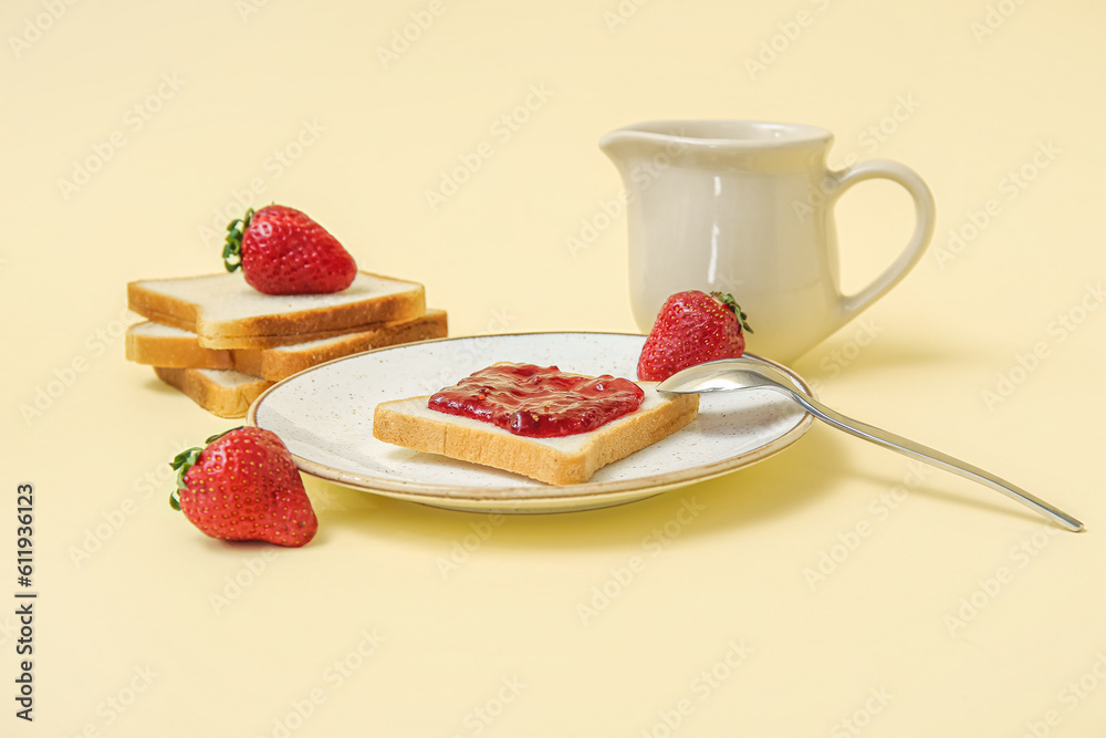 Plate of tasty toasts with strawberry jam and milk in pitcher on pale yellow background