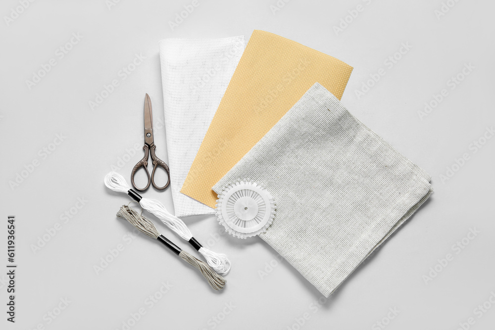 Different canvases with scissors, mouline threads and ball pins on white background