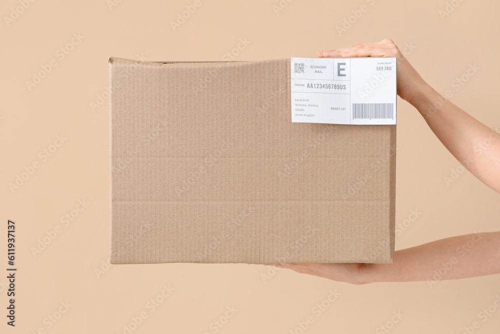 Hands of courier with parcel on beige background