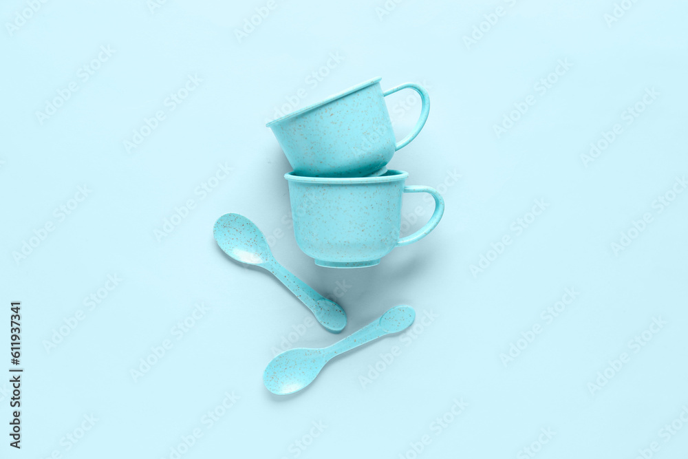 Cups with spoons for baby on blue background