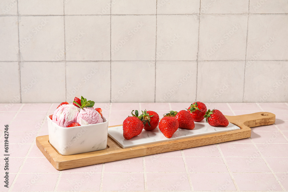 Square bowl of strawberry ice cream with mint, berries and board on pink tile table near white wall