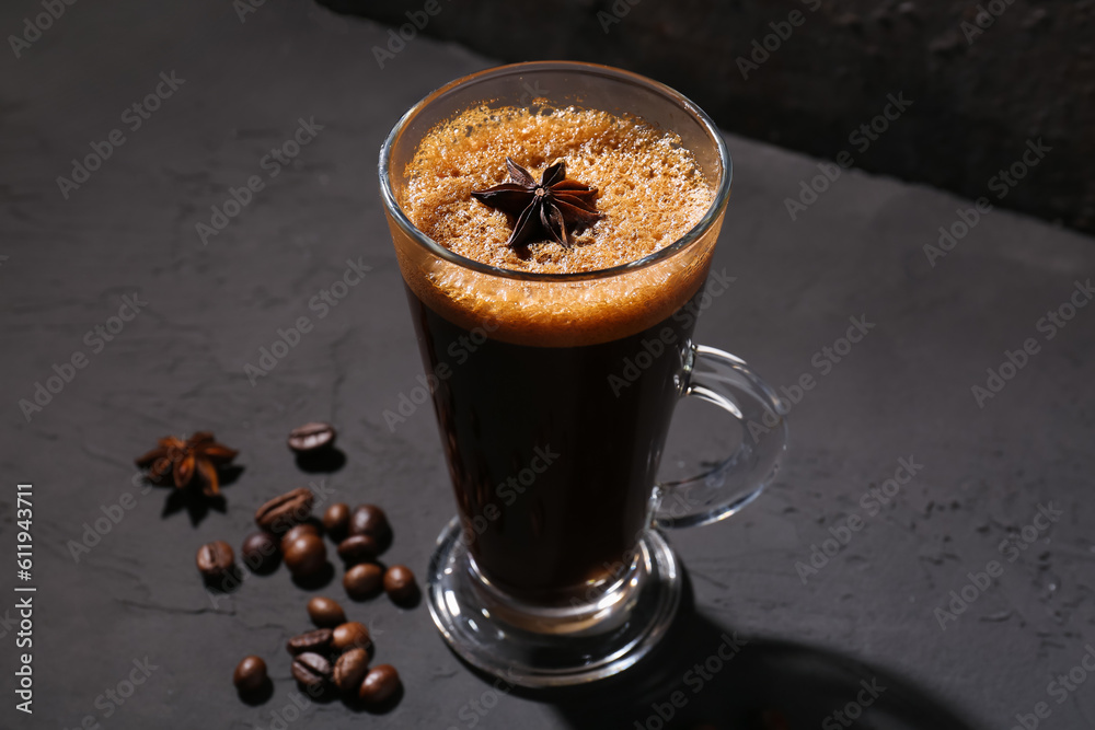 Glass of delicious espresso with star anise and coffee beans on dark background, closeup