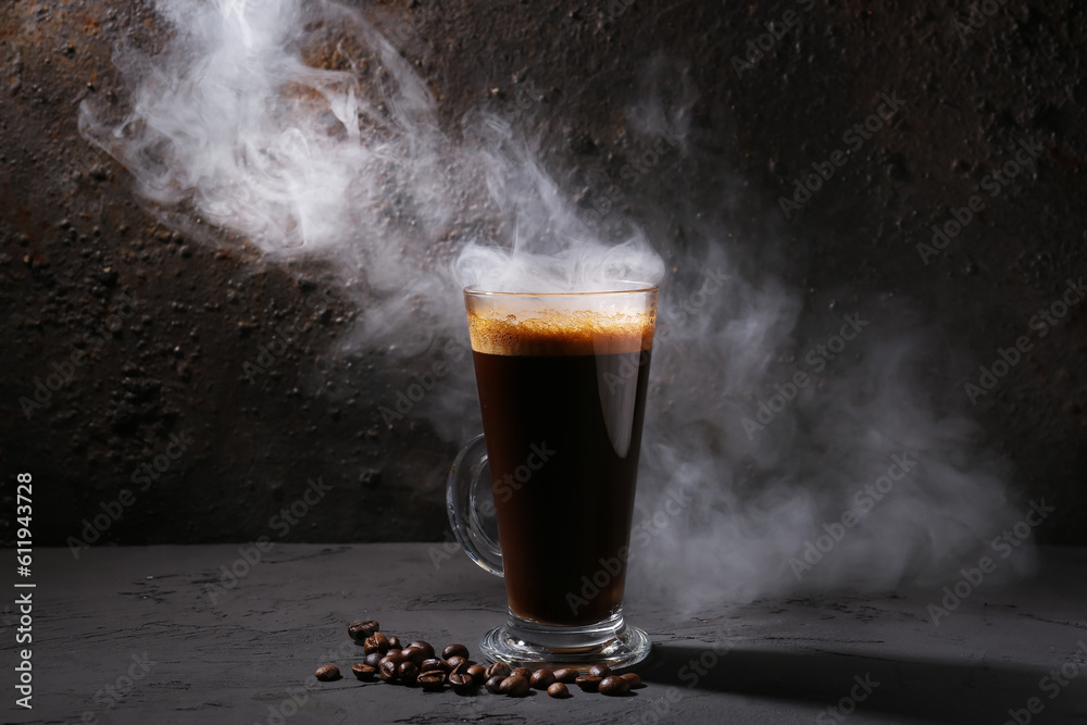 Glass of delicious espresso and coffee beans on dark background