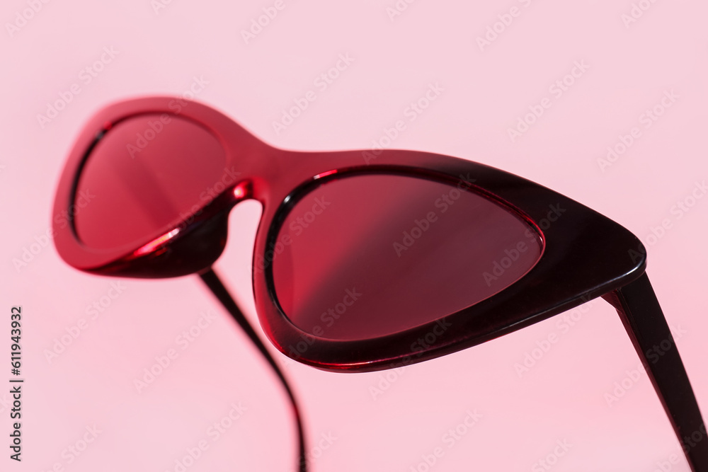 Stylish black sunglasses on pink background, closeup