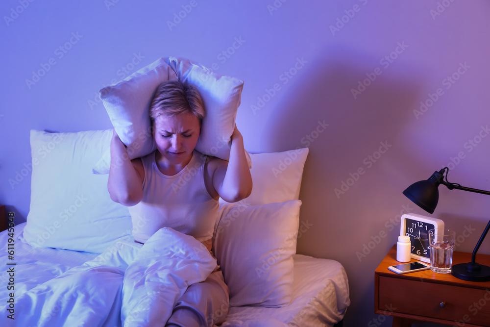 Young woman with pillow cannot sleep in bed at night