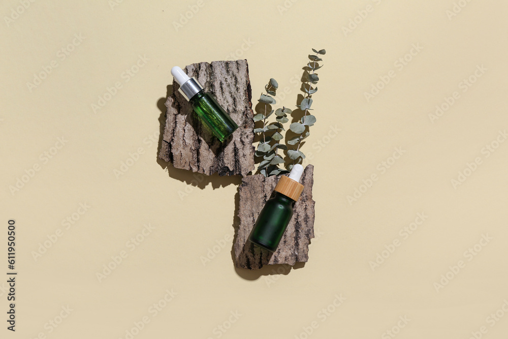 Composition with bottles of essential oil, tree bark and eucalyptus branches on color background