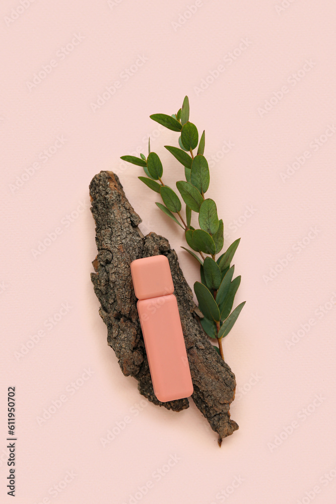 Lipstick, tree bark and eucalyptus branch on color background