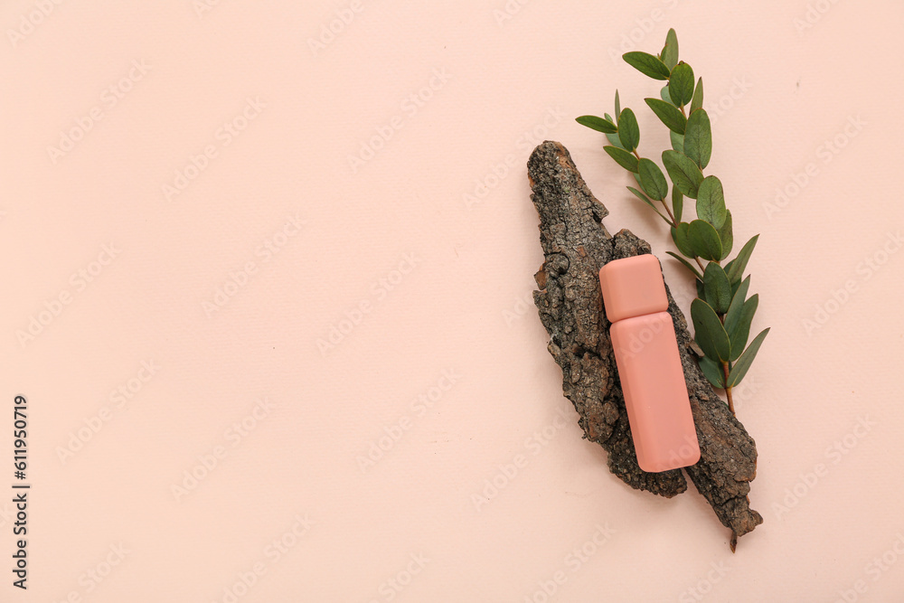 Lipstick, tree bark and eucalyptus branch on color background