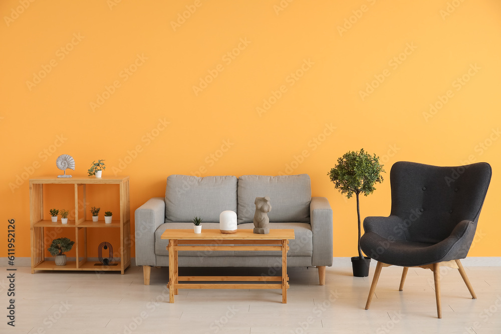 Armchair with couch, coffee table and houseplants near orange wall