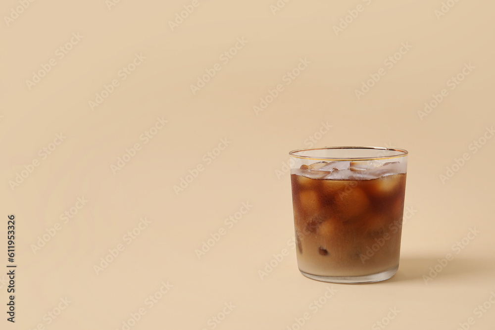 Glass of ice coffee on beige background