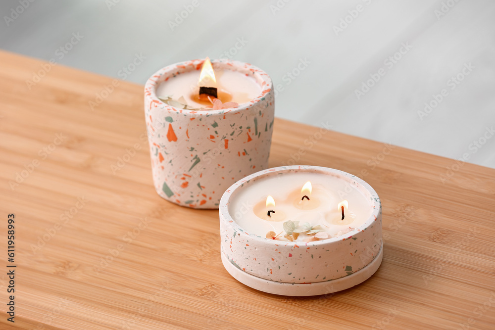 Holders with burning candles on table in room, closeup