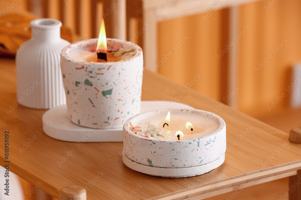 Holders with burning candles on table in room, closeup