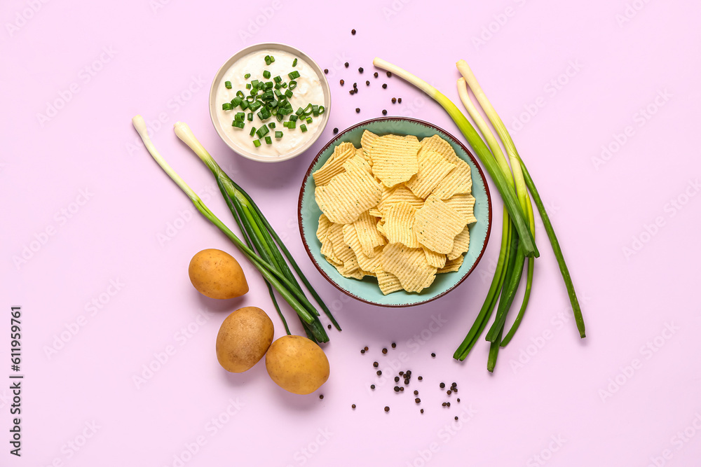 Bowl of tasty sour cream with sliced green onion and potato chips on lilac background