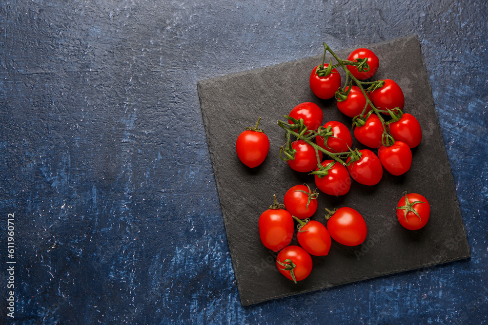 Board with fresh cherry tomatoes on blue background