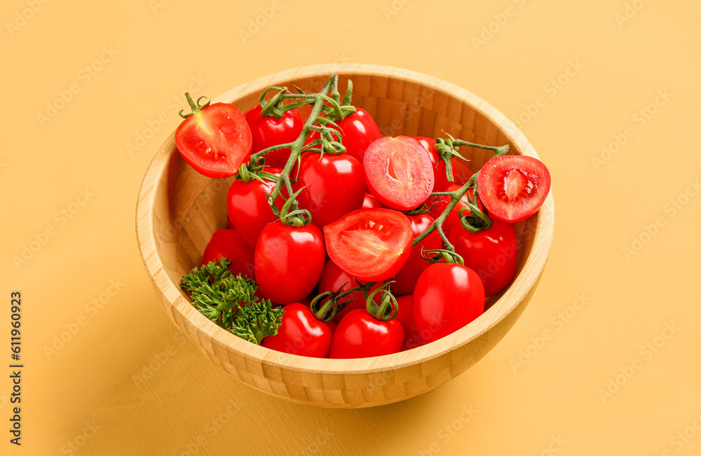 Wooden bowl with fresh cherry tomatoes and parsley on yellow background