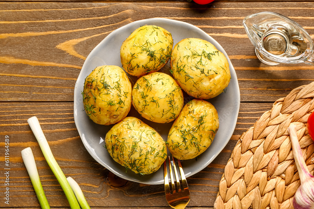 Plate of boiled baby potatoes with dill and green onion on wooden background