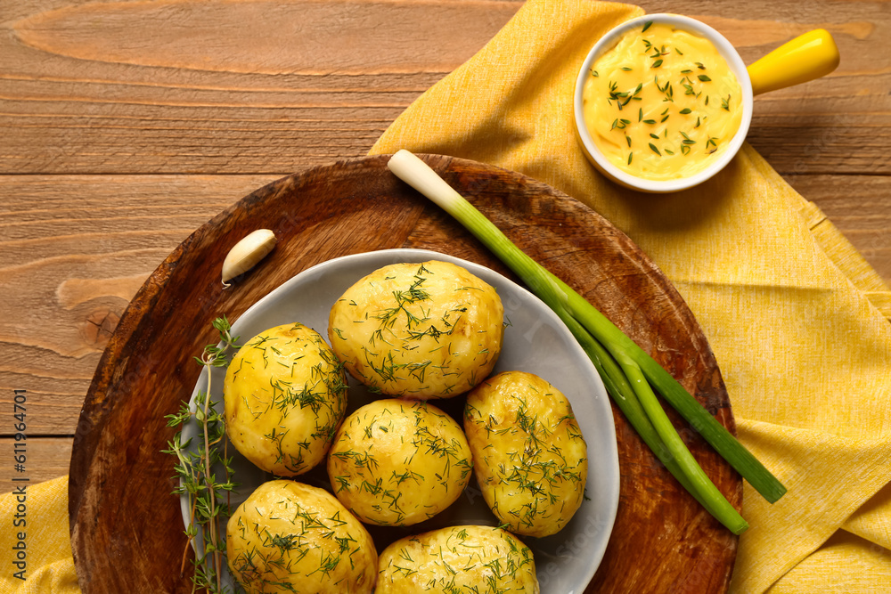 Plate of boiled baby potatoes with dill and green onion on wooden background