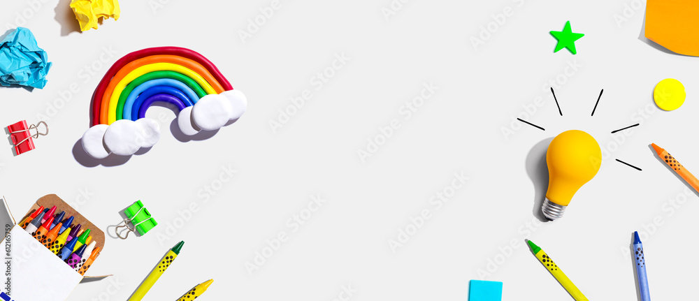 Idea light bulb with a rainbow and school supplies overhead view - flat lay