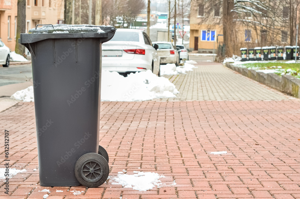 View of black garbage container in city on winter day