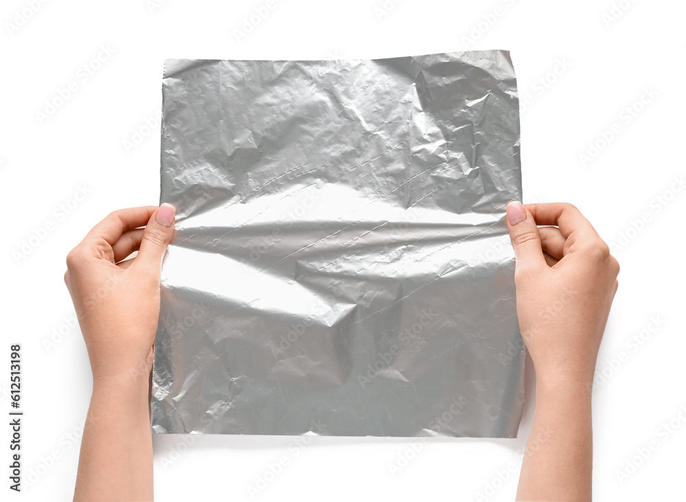 Female hands with sheet of aluminium foil on white background, closeup