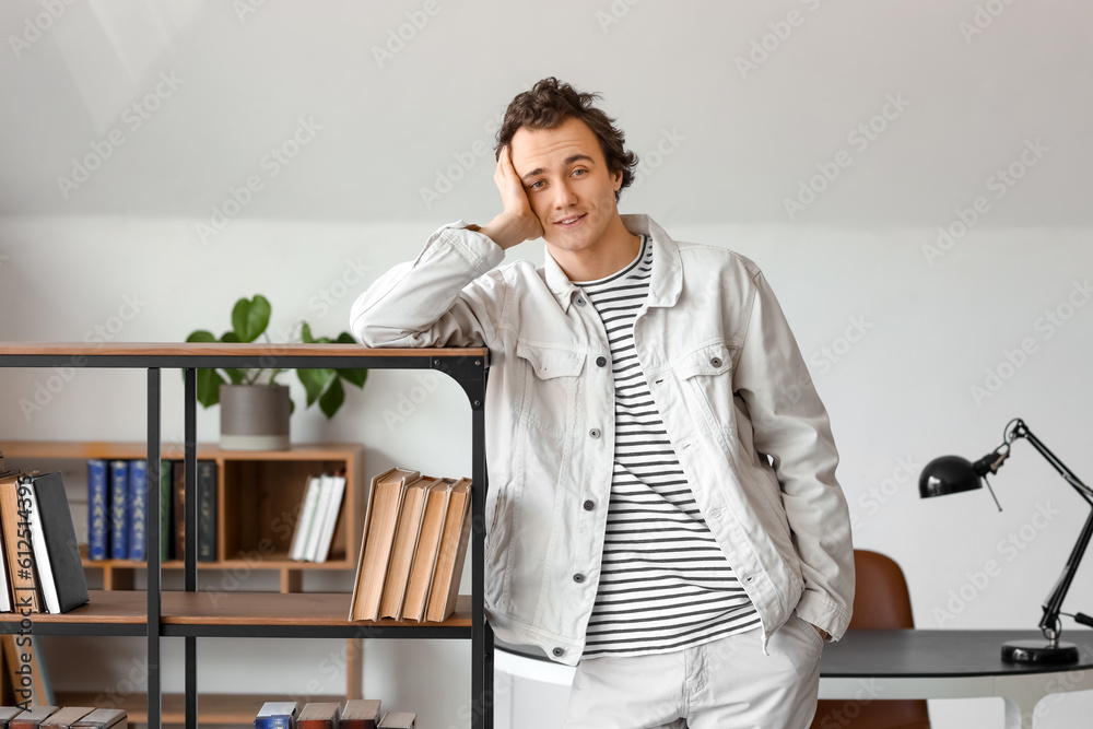 Young man beside bookshelf in library