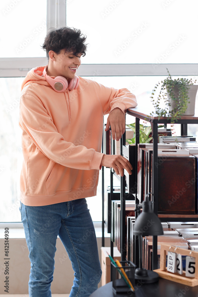 Male student taking book from shelf in library