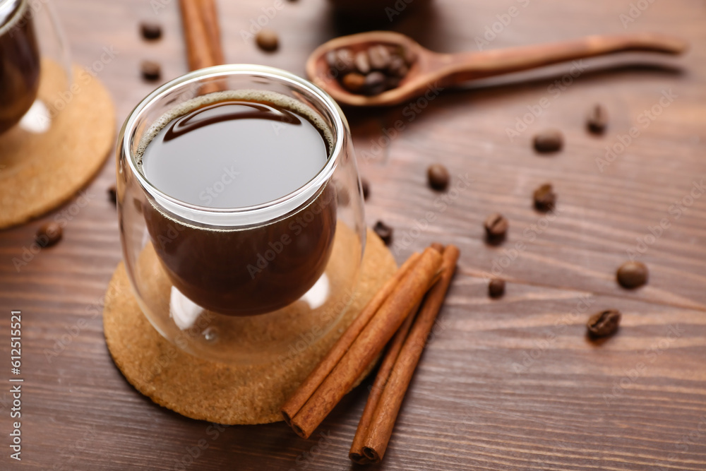 Drink coasters with glass of coffee, cinnamon and beans on wooden table