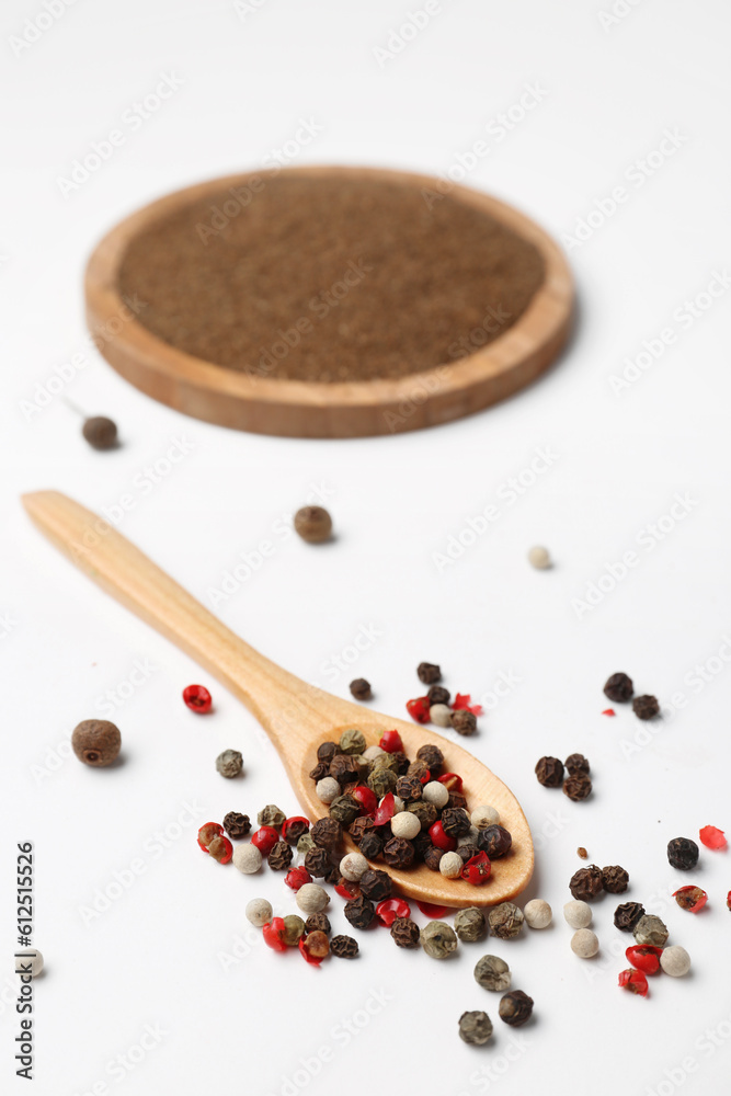 Wooden spoon with aromatic peppercorns on light background