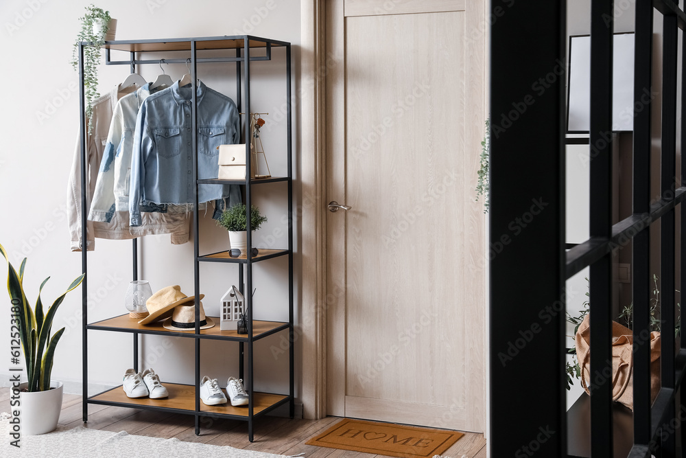 Shelving unit with clothes and accessories in interior of modern hall