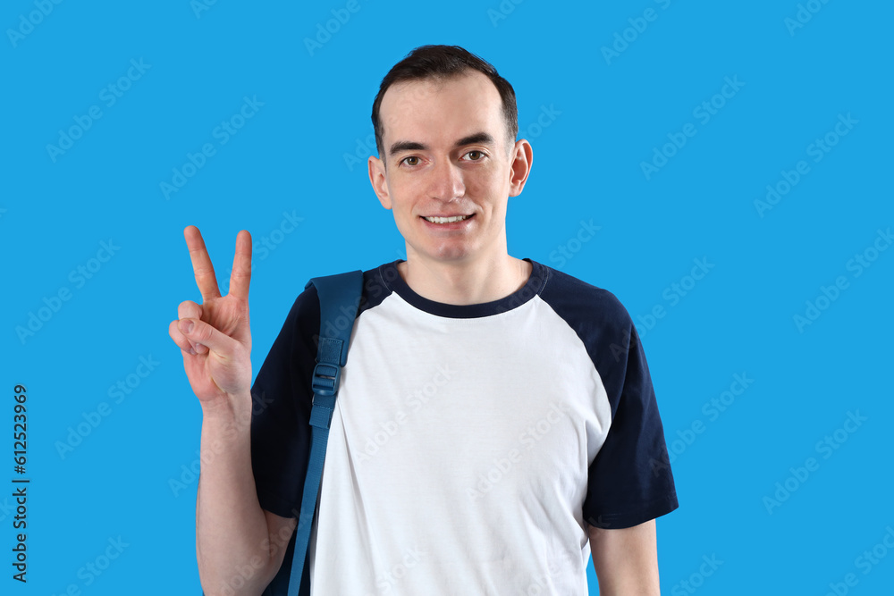 Male student showing two fingers on blue background