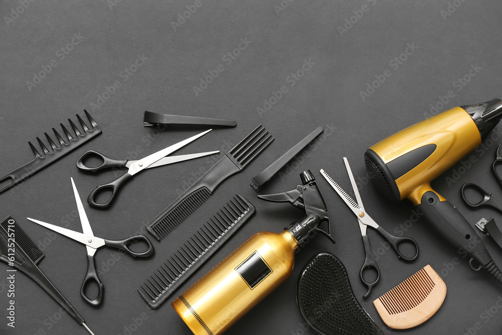 Composition with hairdressing accessories, dryer and spray bottle on black background