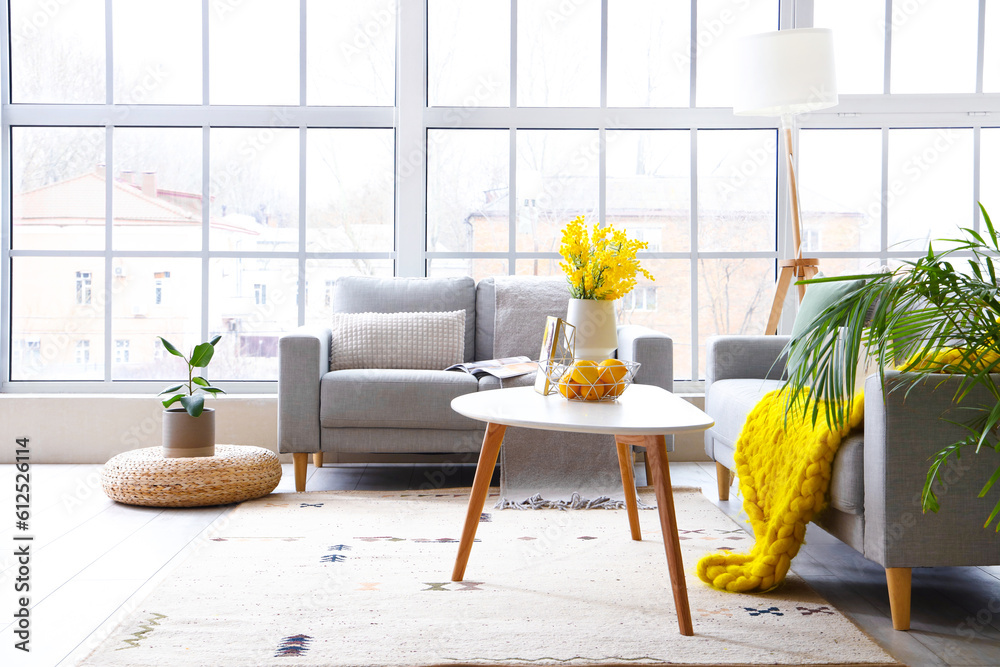 Interior of bright living room with cozy sofas near big window