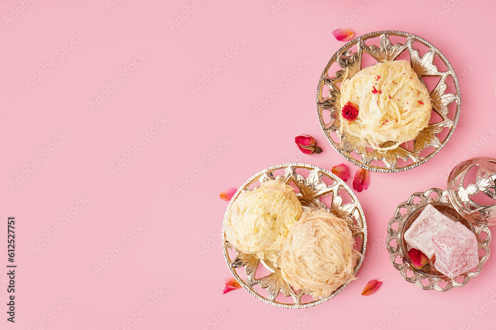 Plates with tasty Turkish Pismaniye and delight on pink background