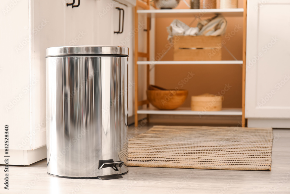 Metallic trash bin on floor in modern kitchen