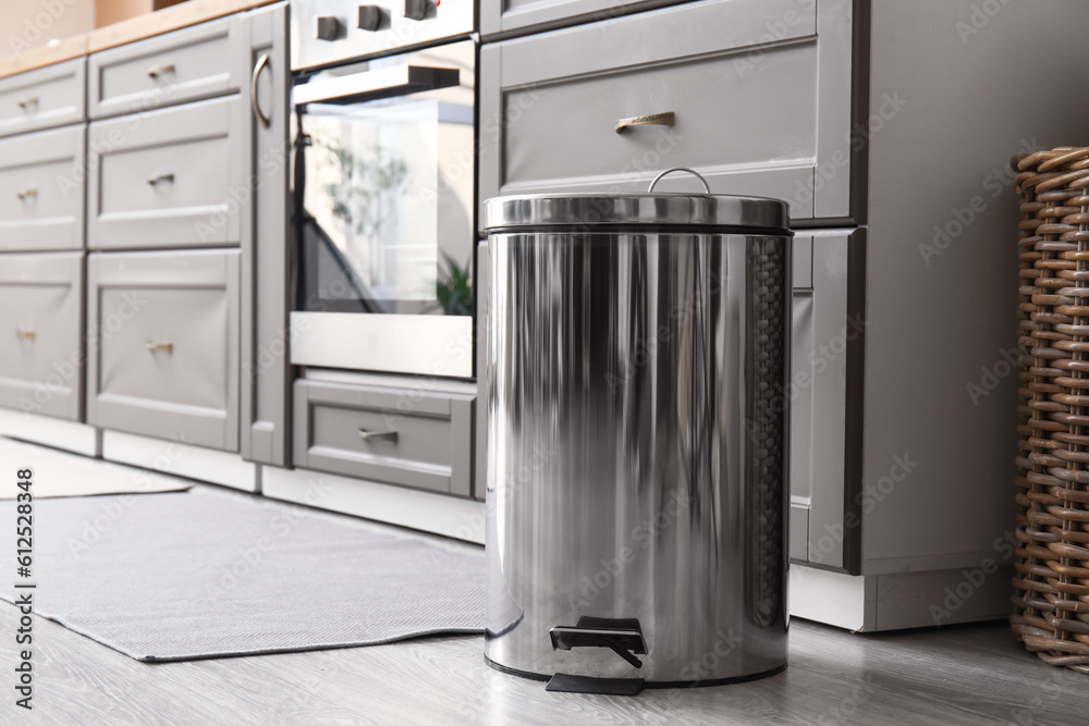 Metallic trash bin on floor in modern kitchen